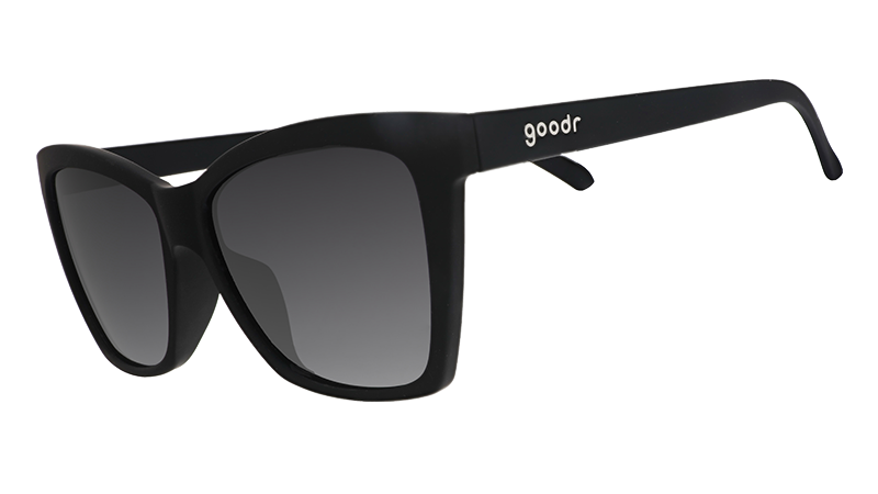 Three-quarter angle view of black angled cat-eye sunglasses with non-reflective black gradient lenses.
